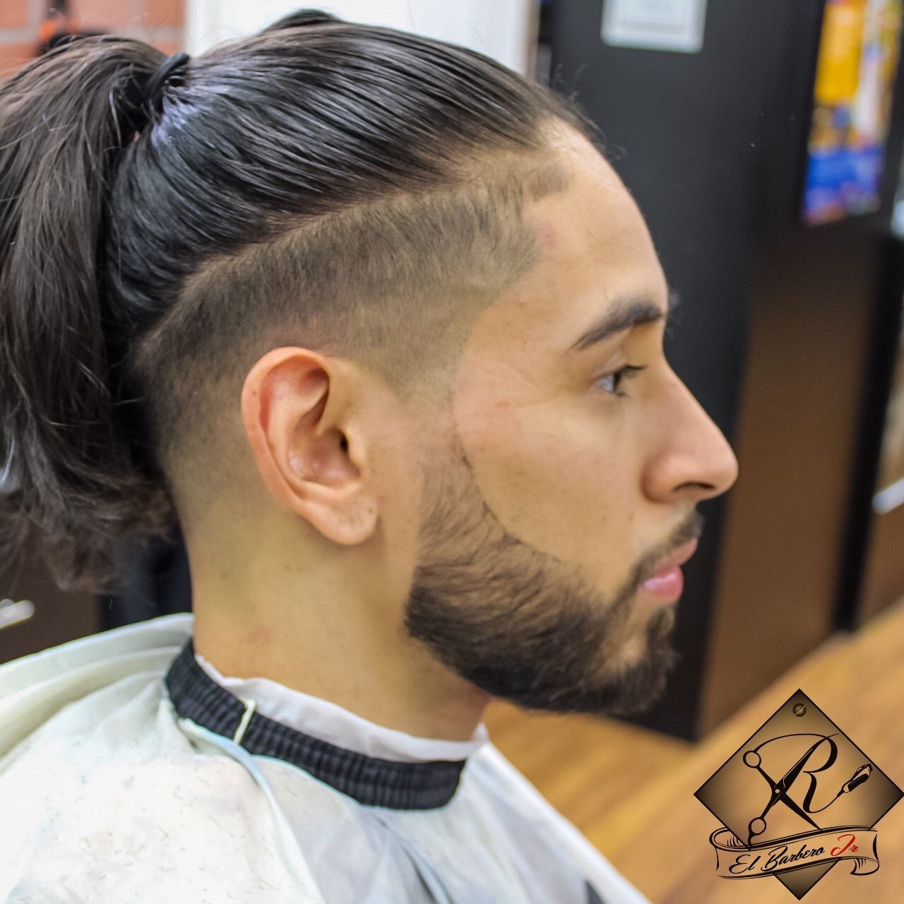 Skin fade with long slicked-back hair and shaped beard